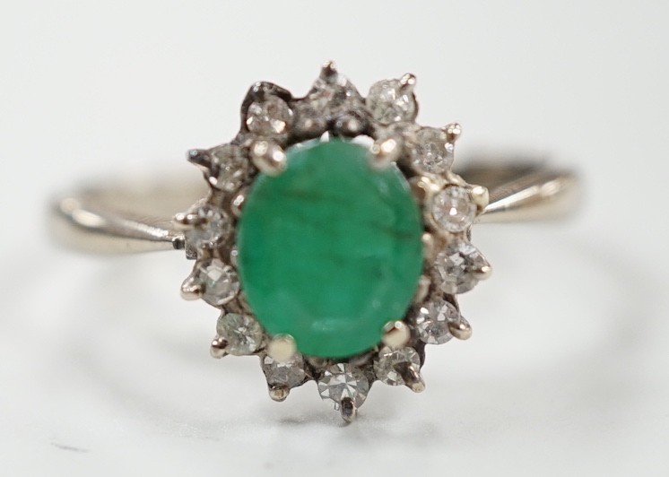 An 18ct, emerald and diamond set oval cluster ring, size O/P, gross weight 3.2 grams.